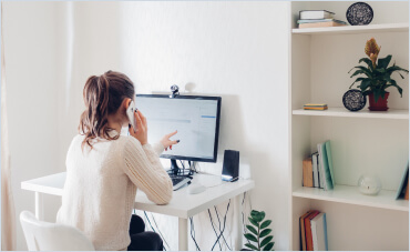 Image of a woman on the phone while looking at computer.