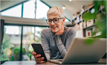 Image of a woman on the computer and  looking at her phone